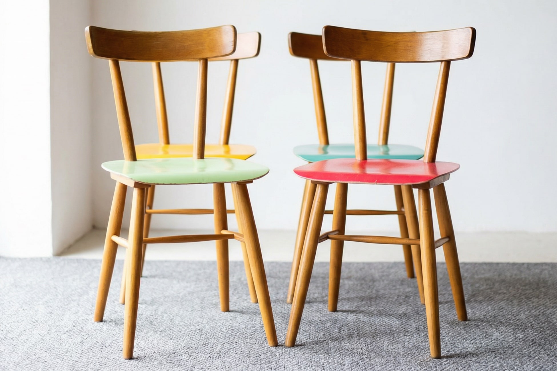 Bunte Küchenstühle in einem modernen Stillleben, angeordnet auf einem grauen Teppich.